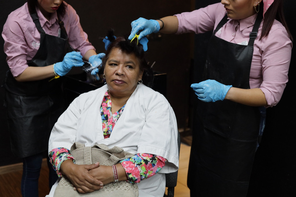 Residentes de Cien Corazones pintan el cabello de una modelo