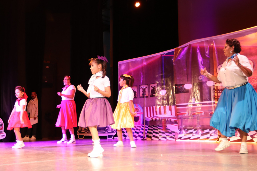 5 mujeres (abuela, hija y nietas) bailando en el escenario,