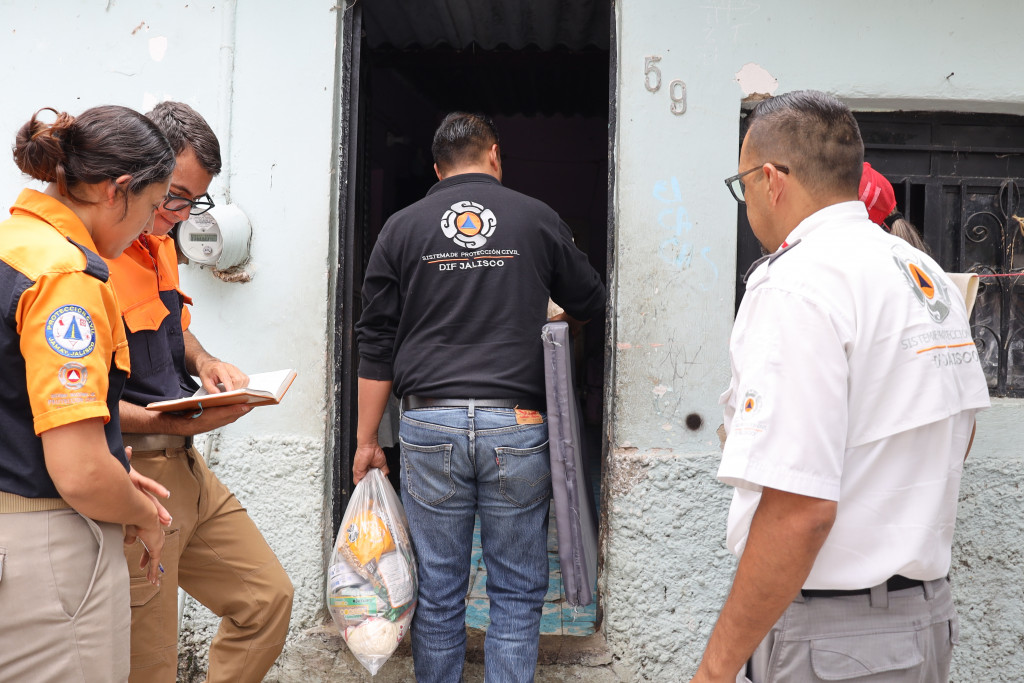 Personal de protección civil entrega colchonceta y despensa a la entrada de una vivienda