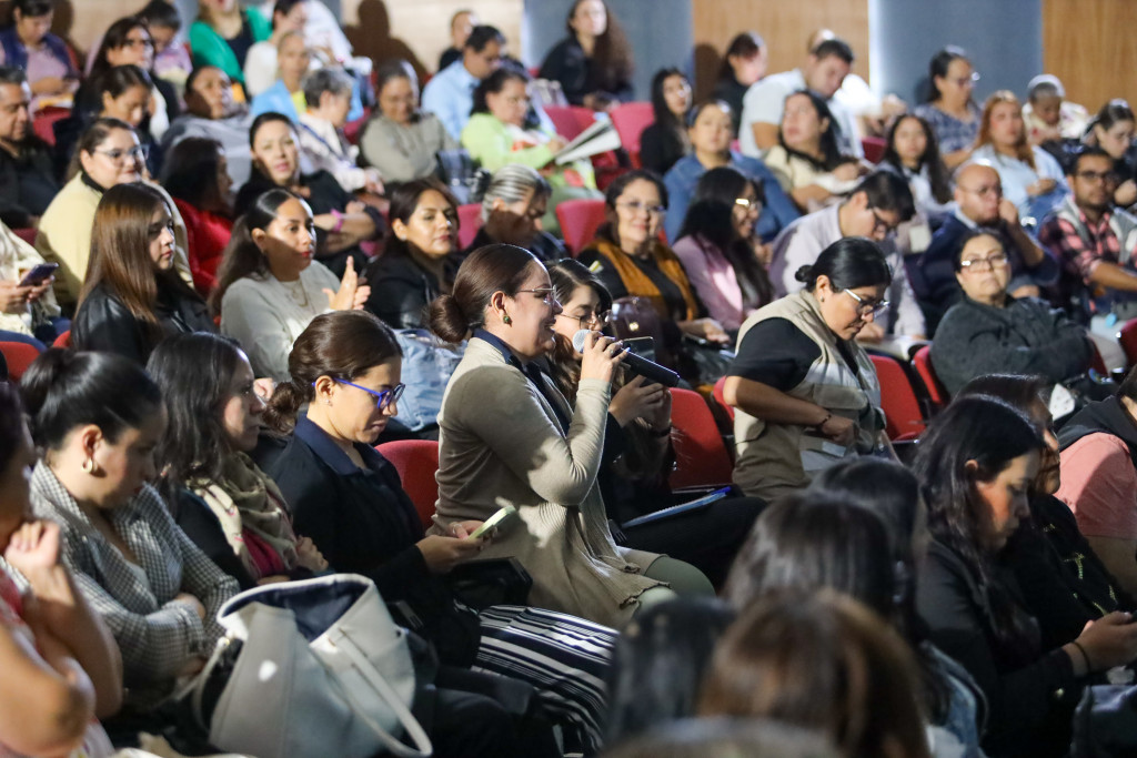 Trabajadoras sociales en las silla, una de ellas al centro una toma la palabra al micrófono