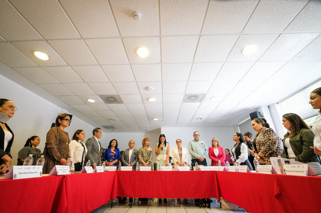 Integrantes de la Subcomsión de pie, alrededor de una mesa acomodada en herradura, al centro la Procuradora Sandra Trelles hace uso de la voz, a su lado Diana Vargas y Thais Loera