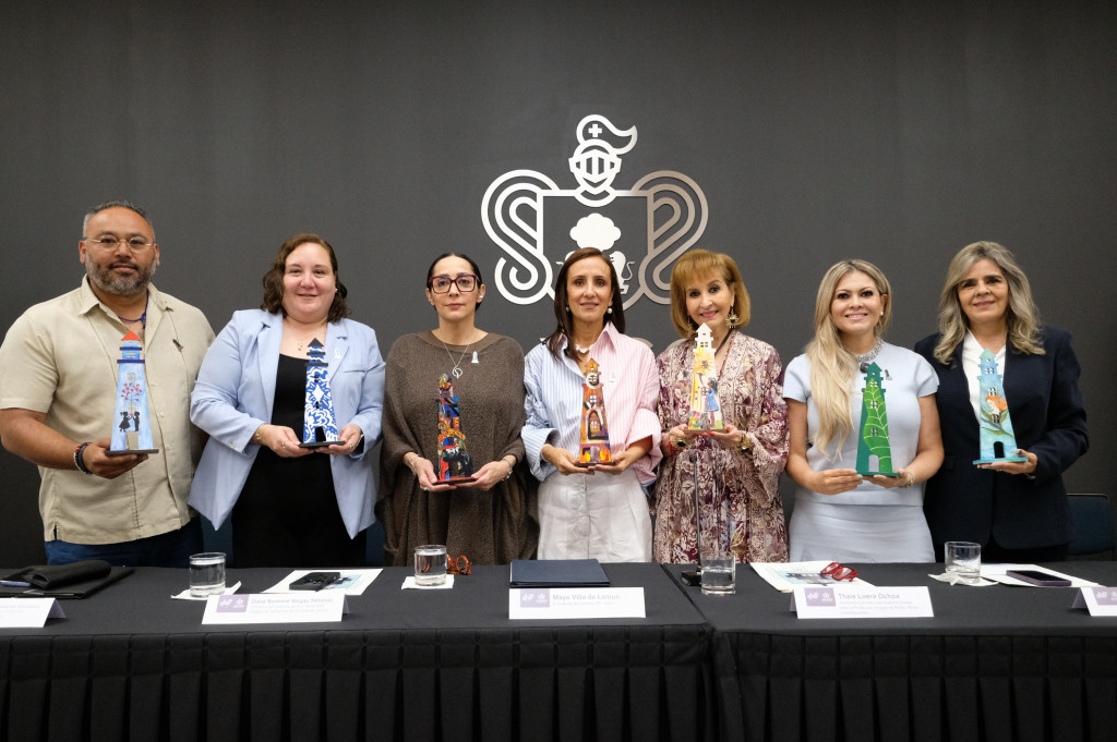 foto oficial de autoridades sosteniendo en sus manos una estatuilla del faro de la esperanza intervenida por artistas locales