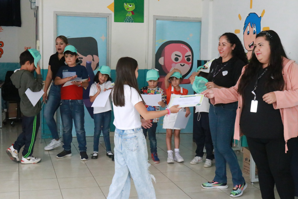 Maestras entregan Diploma a una niña asistente al taller
