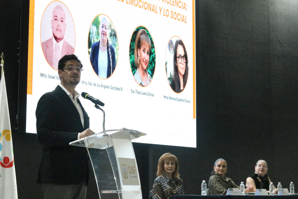 León Delgadillo en podio expone a la audiencia, al fondo se observa a los integrantes del presidium